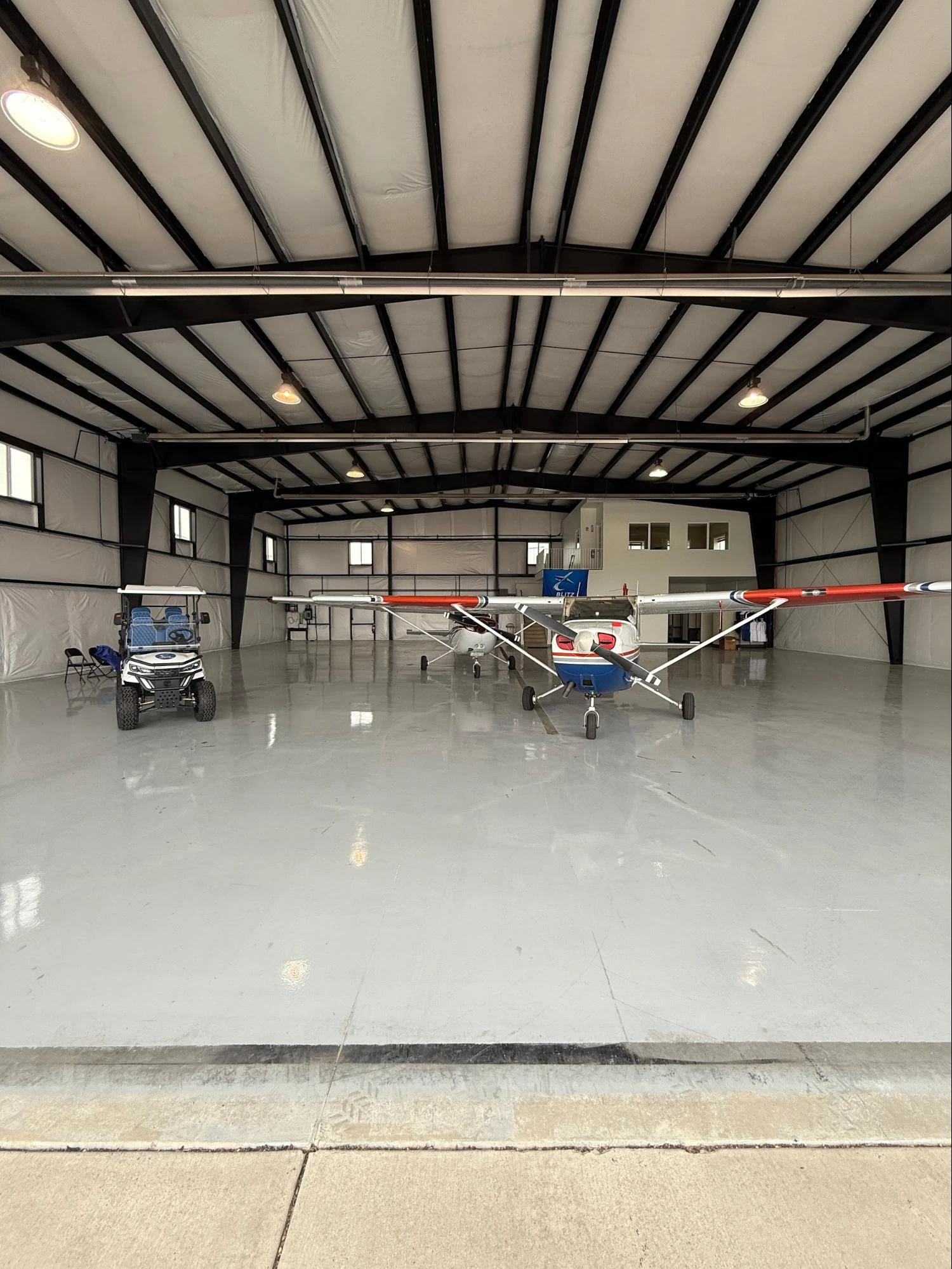 Inside the Blitz Aviation hangar with a Cessna 172 and a utility cart on a clean concrete floor